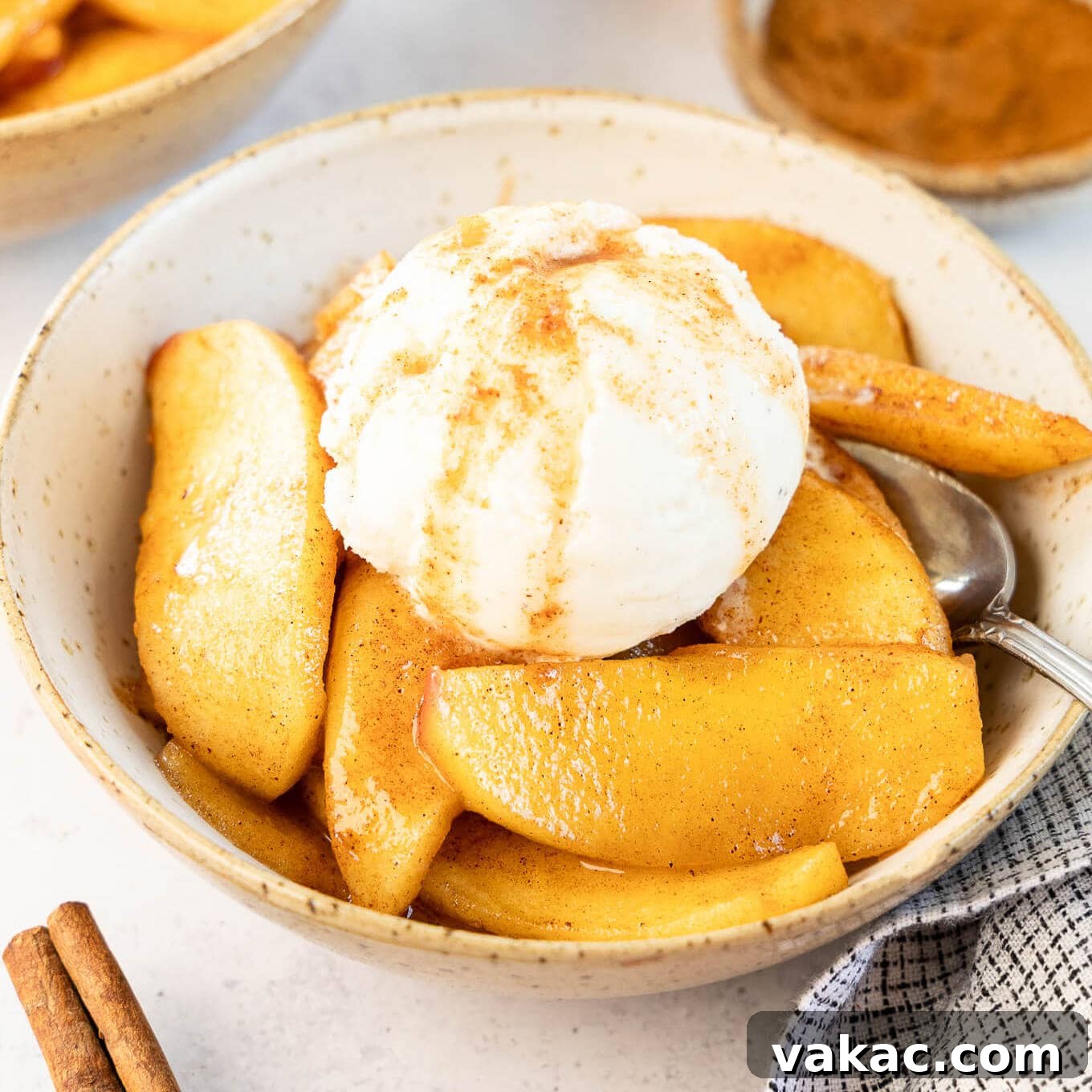 A bowl of fried apples topped with a scoop of ice cream.