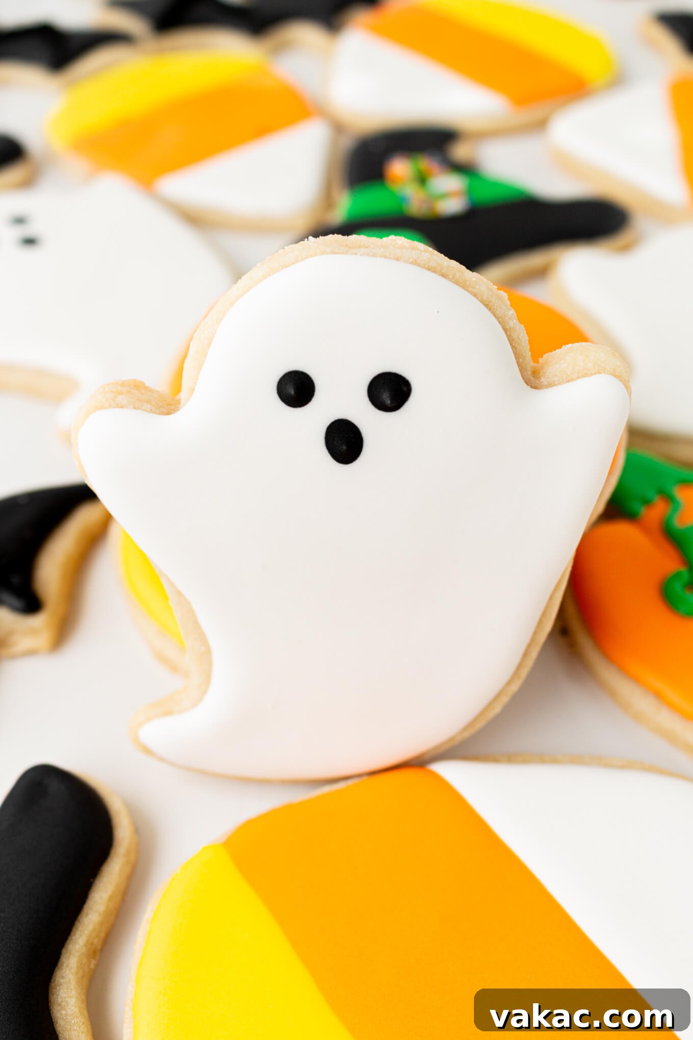 Ghoulishly Good Sugar Cookies 9 A beautifully iced ghost sugar cookie, with black eyes and mouth, surrounded by other decorated Halloween cookies.