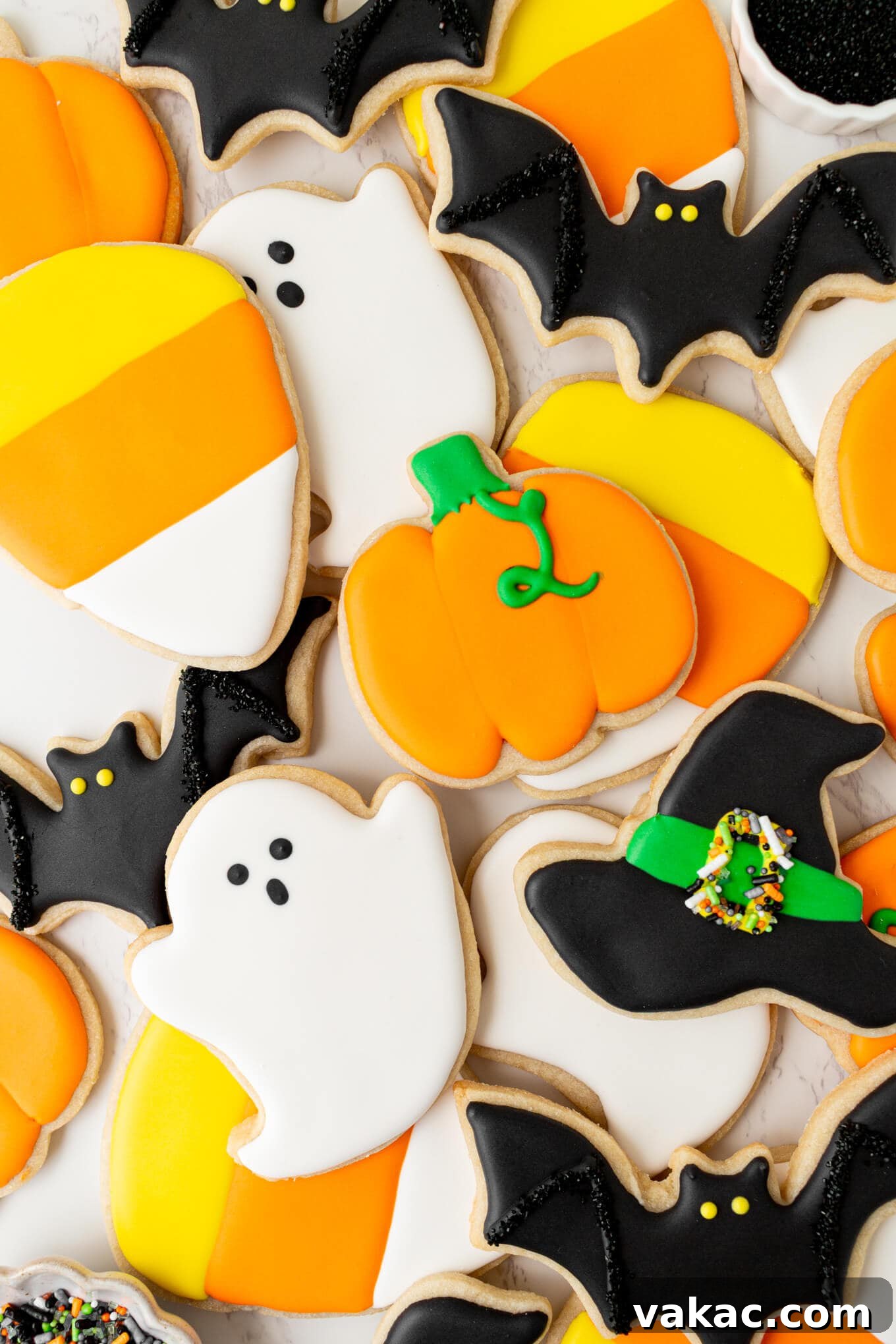 Ghoulishly Good Sugar Cookies 8 An overhead view of a collection of beautifully iced Halloween sugar cookies in various festive shapes on a white surface.