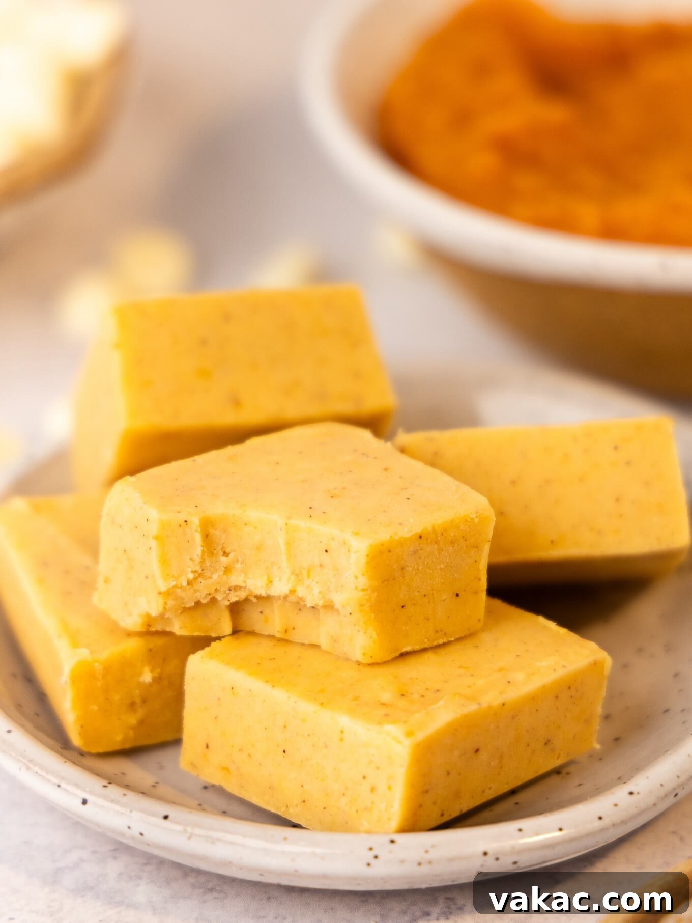 Spiced Pumpkin Fudge 9 Slices of pumpkin fudge on a plate. One has a bite missing.