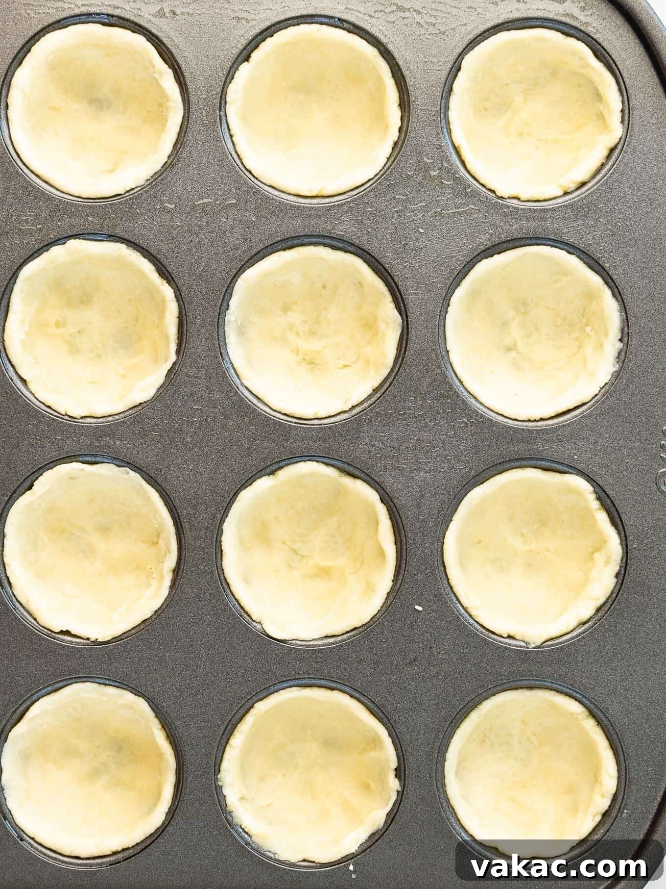 Southern Pecan Treasures 5 An overhead view of the cream cheese crust dough perfectly pressed into individual cavities of a mini muffin pan, forming neat cups.