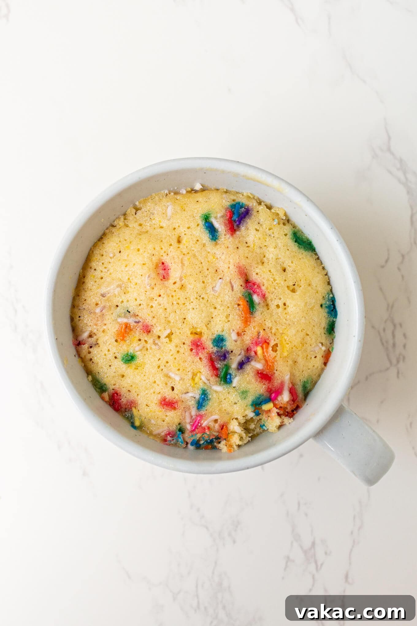 Cozy Vanilla Mug Treat 5 A freshly baked, perfectly risen vanilla cake nestled warm inside a ceramic mug, showcasing its golden-brown top.