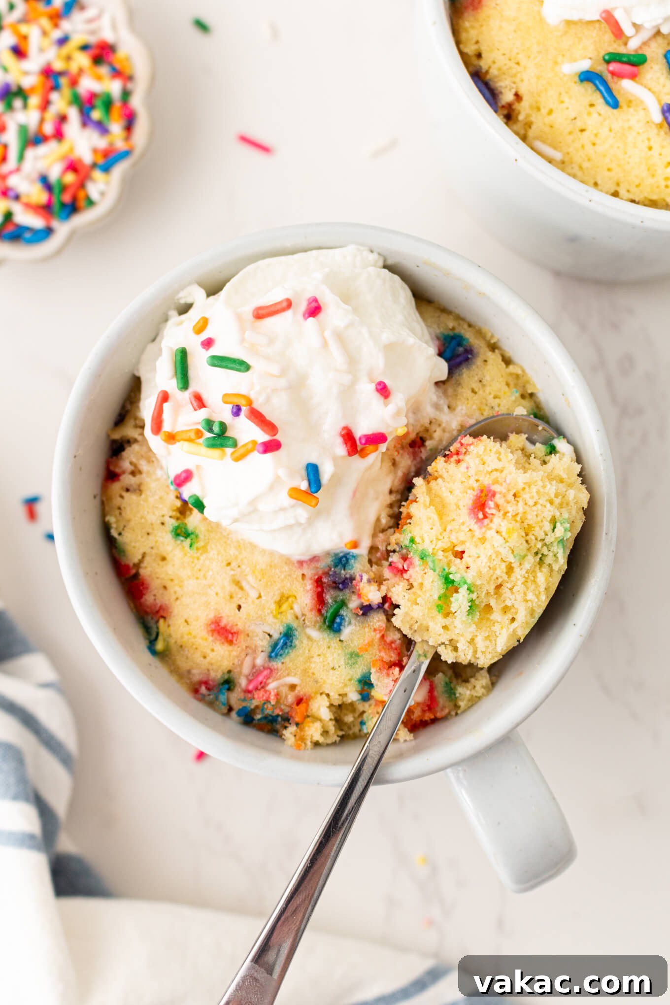 Cozy Vanilla Mug Treat 6 An inviting overhead view of a vanilla mug cake, elegantly topped with a generous swirl of whipped cream, making it a delightful and comforting dessert.