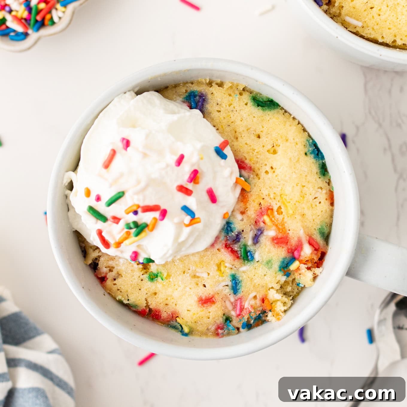 A vanilla mug cake topped with whipped cream.