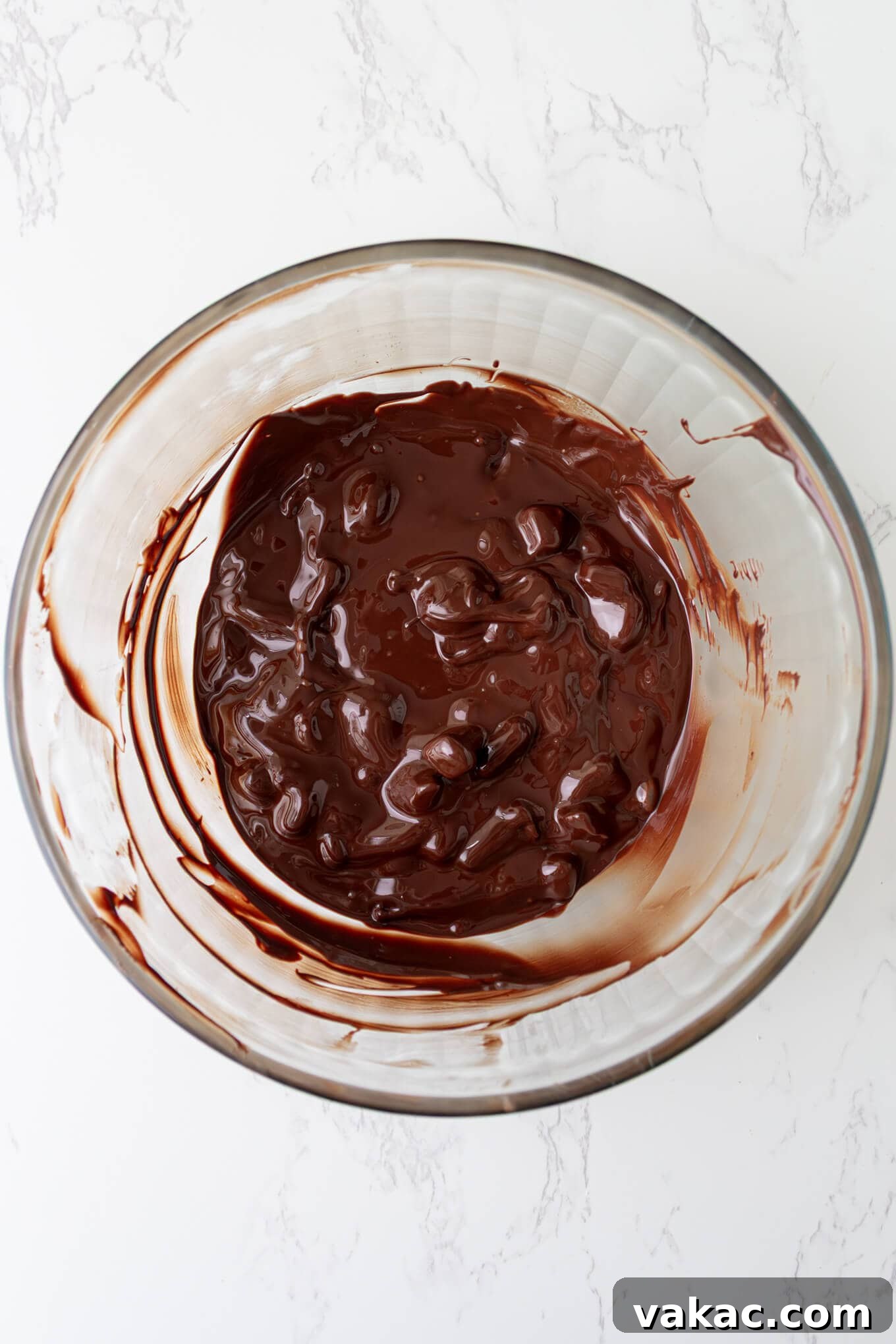 Twisted Chocolate Indulgence 6 Melted chocolate being seeded with additional finely chopped chocolate pieces in a glass bowl.
