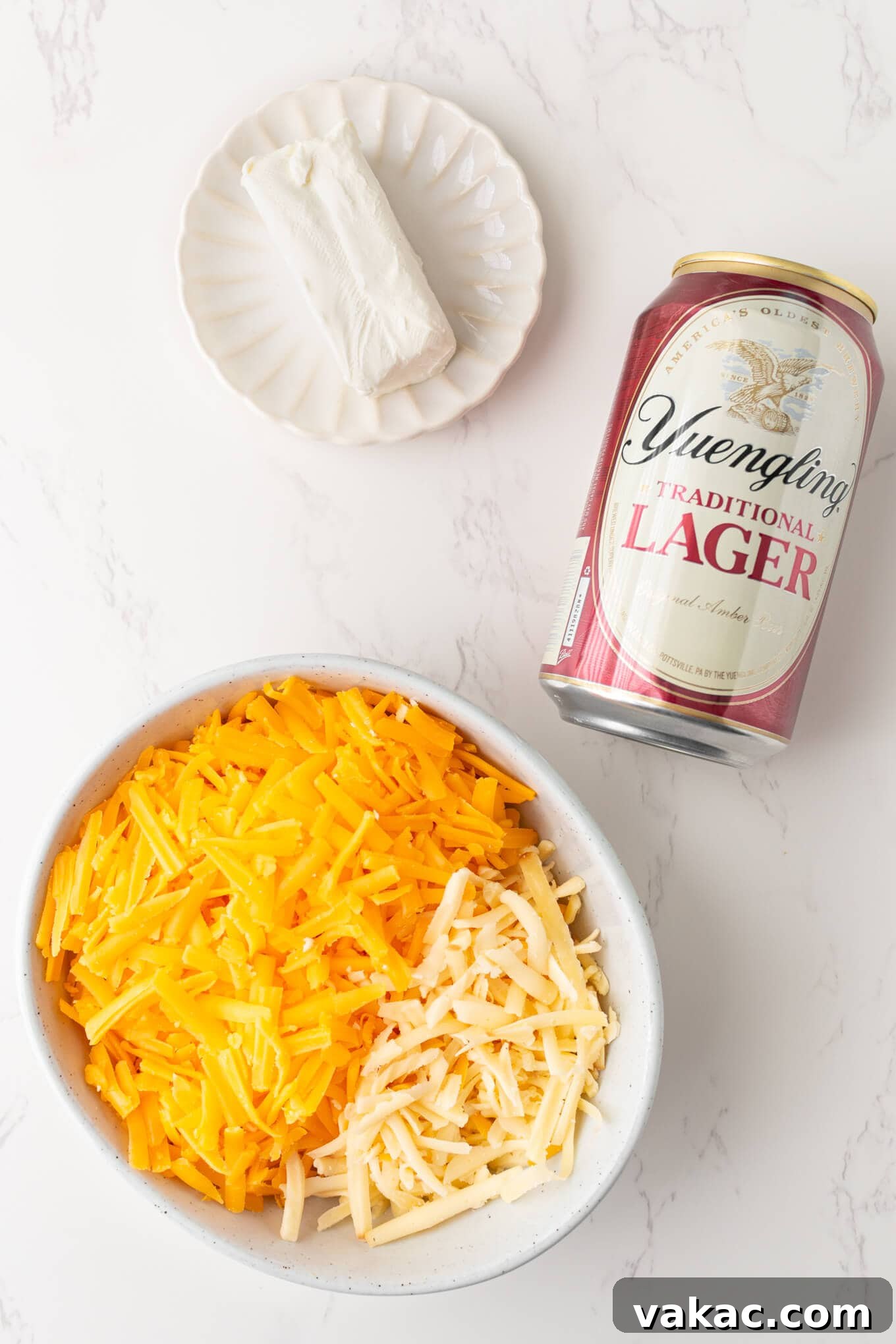 Golden Beer Cheese Dip 3 An overhead view of essential ingredients for beer cheese dip: cream cheese, shredded cheddar, and a can of beer.