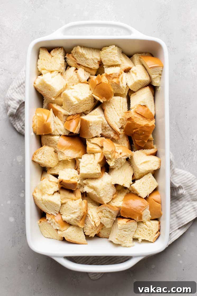 A white 9x13 baking pan filled with evenly cubed day-old bread, ready for the custard.
