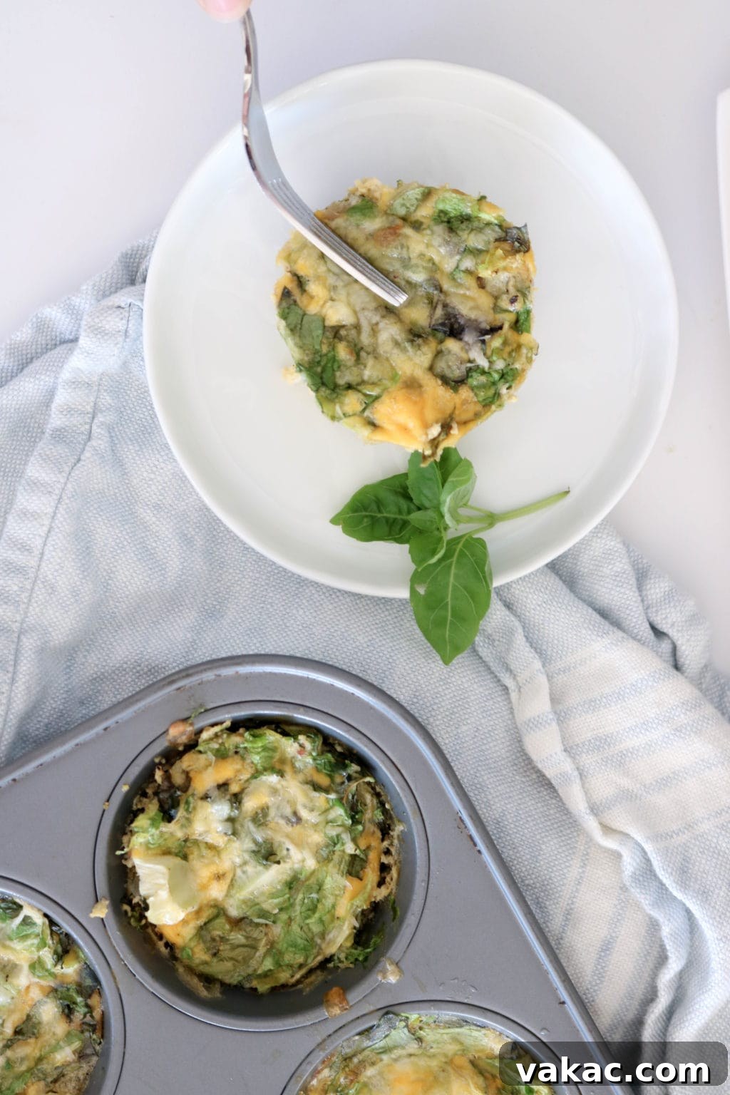 Easy Meal Prep Egg Muffins 5 Muffin tin frittata ingredients laid out on a white sheet. Ingredients include herbs, onion, eggs, cheese, sea salt.