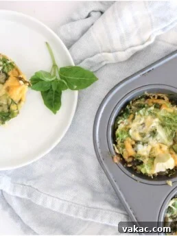 A round white plate with a frittata placed over a light blue kitchen towel and muffin tin filled with frittatas. Ingredients include egg, greens, onion, basil, cheese.