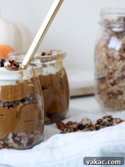 Two jars filled with Deconstructed Pumpkin Pie on a counter with a white kitchen towel and a jar of granola and pumpkins in the background. Ingredients include pumpkin, nut milk, prunes, maple syrup, vanilla.