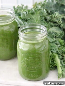 Two mason jars filled with green juice are sitting on a counter.