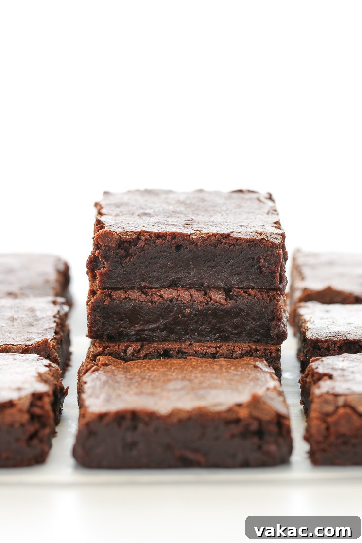 Fudgy Homemade Brownie Delights 2 A stack of sliced fudgy brownies on parchment paper with additional brownies surrounding them. They look rich and moist.