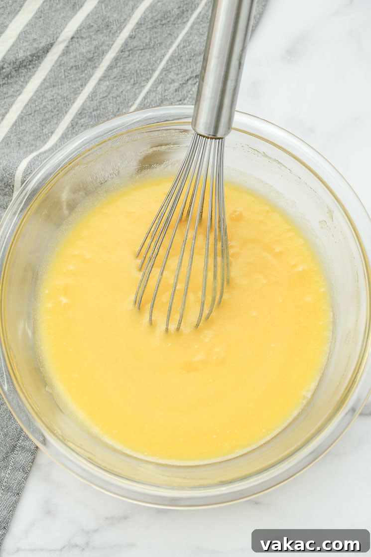 A clear bowl filled with the wet ingredients for fudgy brownies, showcasing their smooth texture.