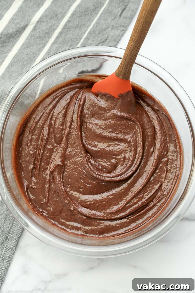 Fudgy Homemade Brownie Delights 3 A clear bowl filled with homemade brownie batter and a rubber spatula, ready for pouring.