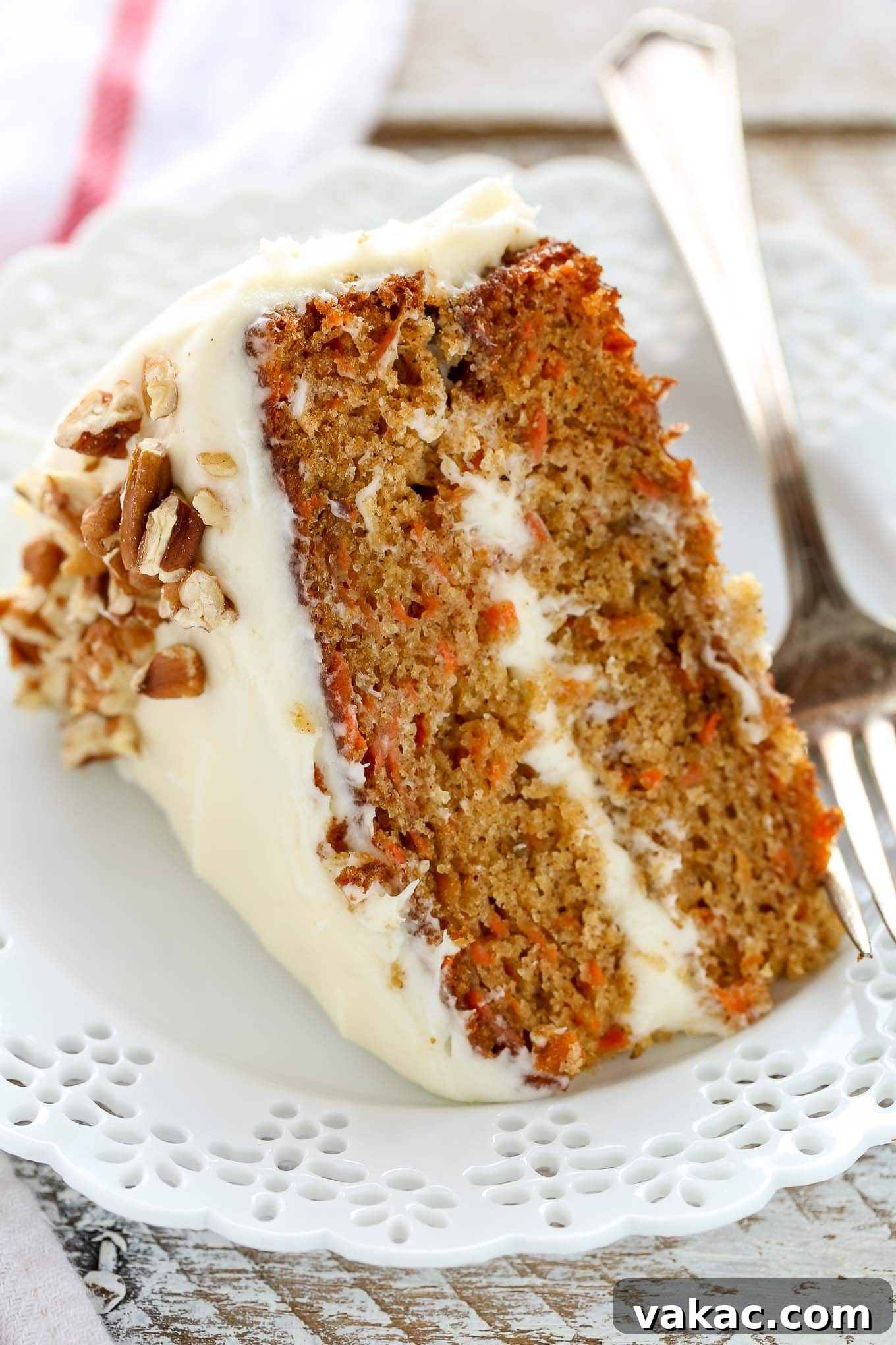 A close up of a slice of carrot cake on a decorative white plate.