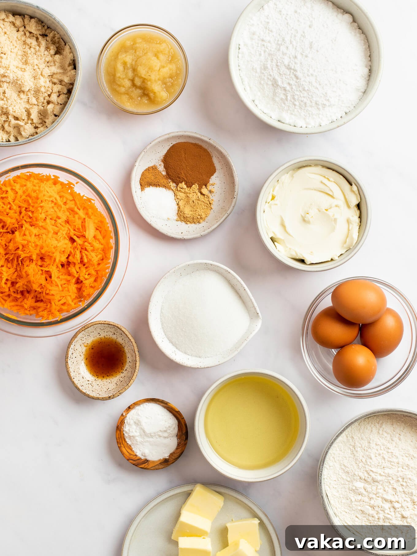 An overhead view of the ingredients for carrot cake on top of a marble surface.