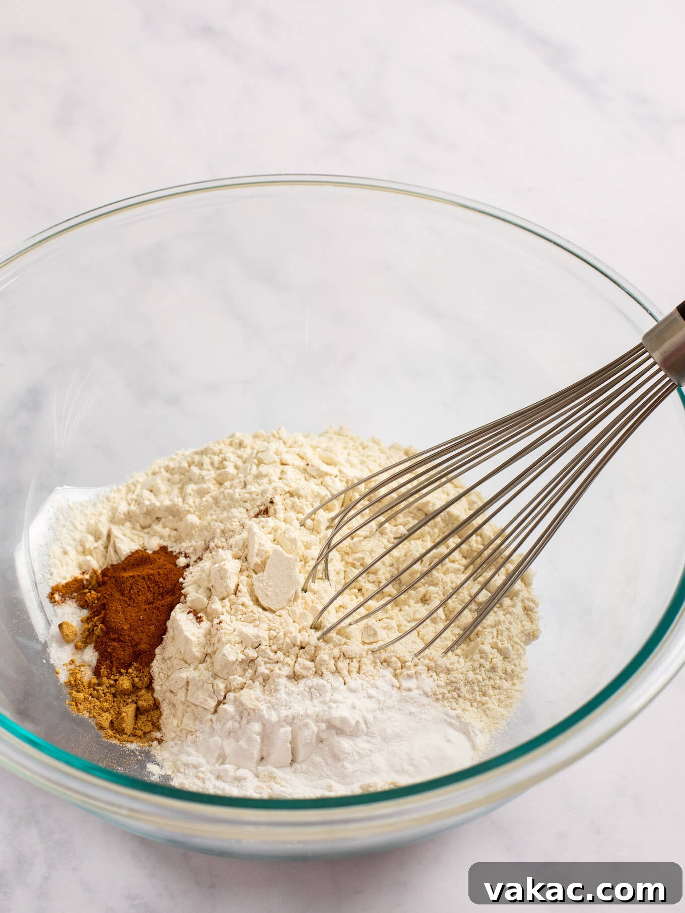 Flour, spices, baking powder, baking soda, and salt in a glass mixing bowl.
