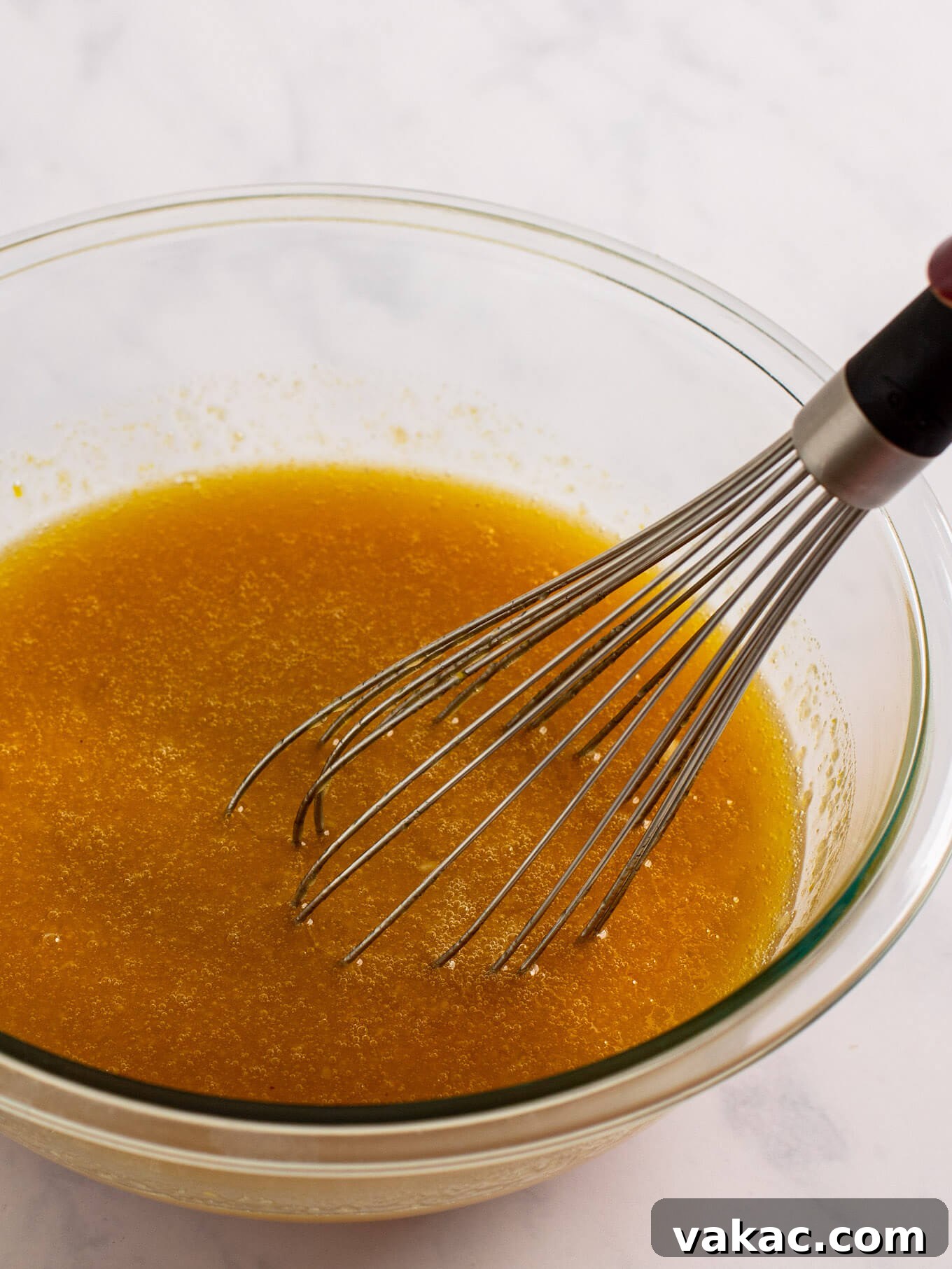 The wet ingredients for carrot cake whisked together in a glass mixing bowl.