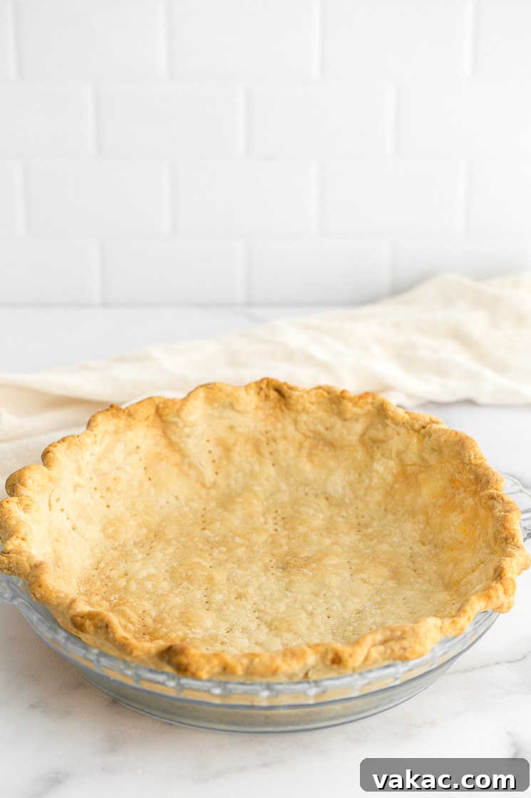 A homemade pie crust in a pie dish sitting on top of a marble surface.