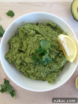 Close-up photo of freshly made Broccomole in a small bowl, garnished with a sprig of fresh cilantro, highlighting its vibrant green color and creamy texture.