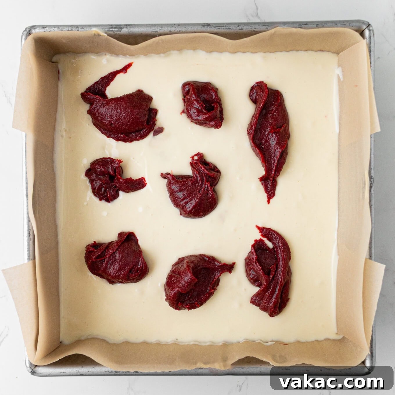 Crimson Cheesecake Brownie Bliss 5 A creamy cheesecake layer adorned with strategic dollops of red velvet brownie batter, prepped for swirling.