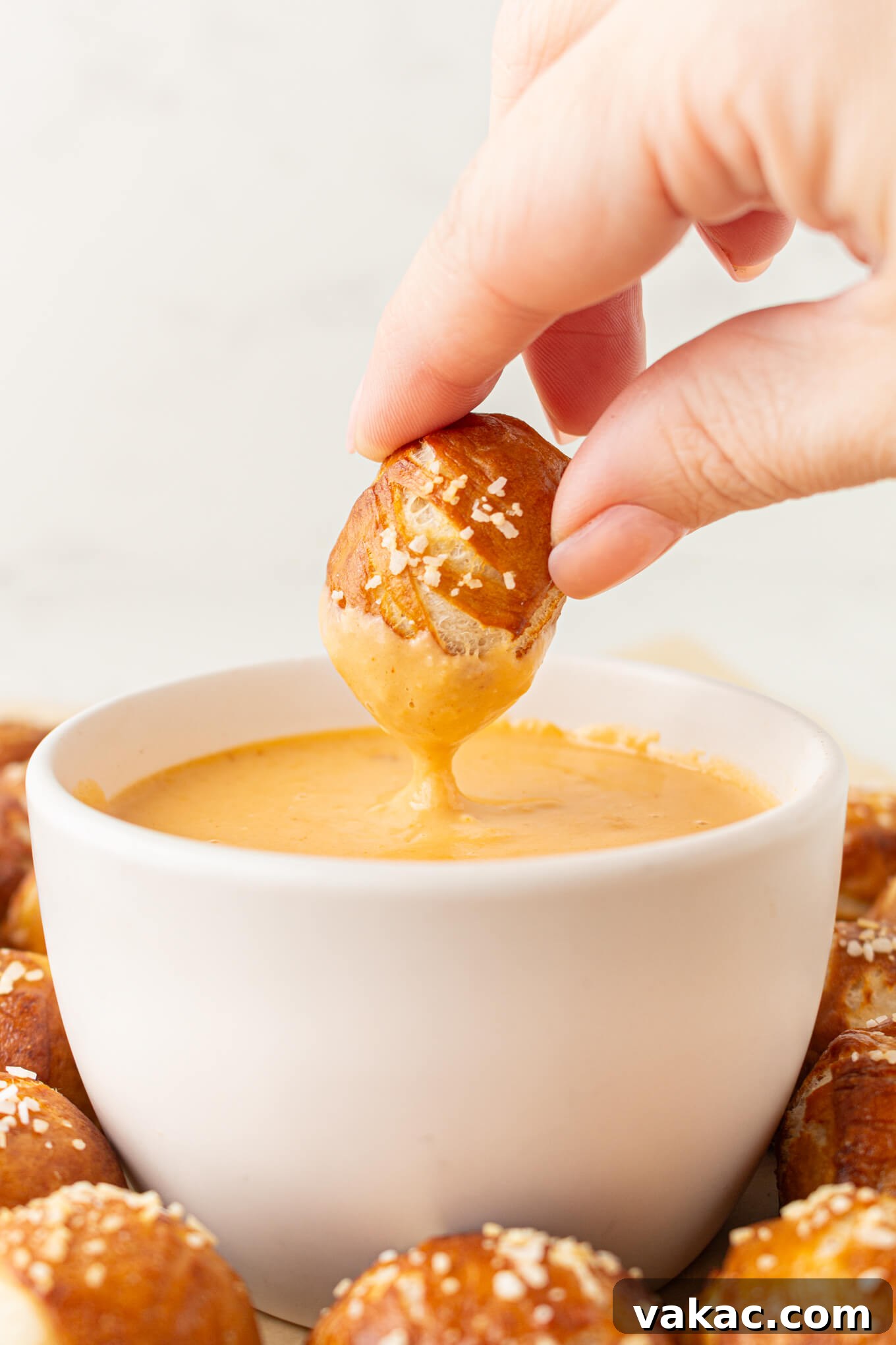 Pillowy Pretzel Gems 9 A freshly baked soft pretzel bite being dipped into a rich, creamy beer cheese dip.