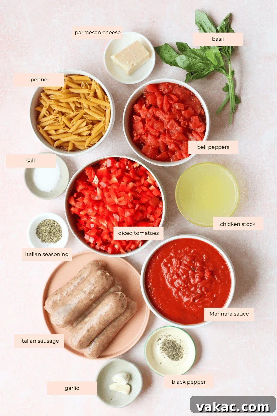 One Pan High Protein Sausage and Pepper Baked Pasta 3 Top-down view of labeled ingredients for a high protein pasta bake, including penne, diced tomatoes, bell peppers, marinara sauce, Italian sausage, chicken stock, parmesan cheese, basil, garlic, salt, pepper, and Italian seasoning.