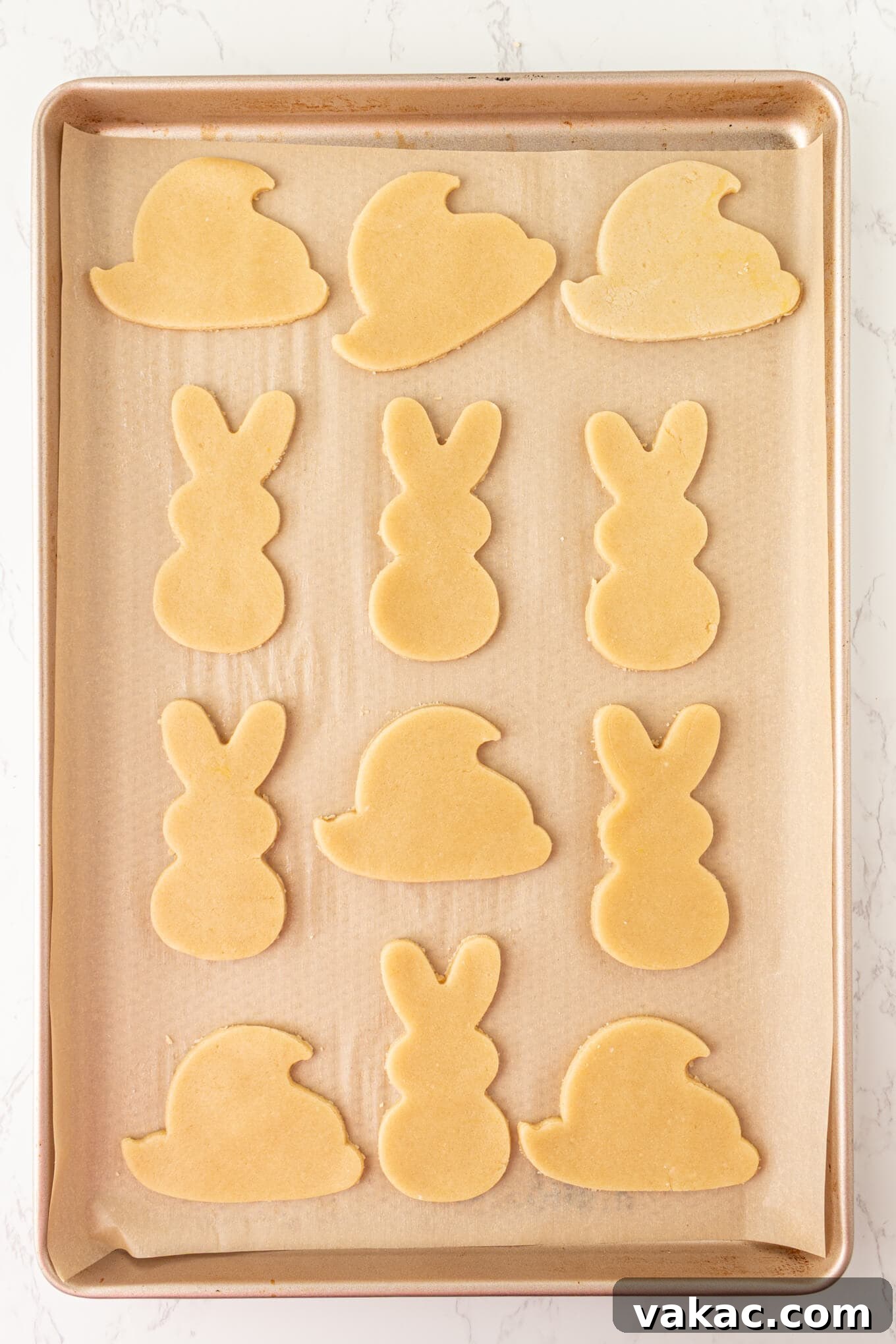 Hoppy Easter Cookies 4 Freshly cut sugar cookie dough in charming bunny and chick shapes, meticulously arranged on a parchment-lined baking sheet, awaiting their turn in the oven.