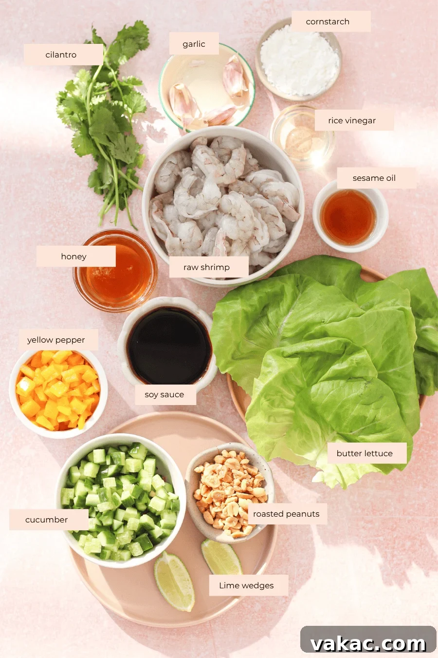 Honey-Soy Shrimp Lettuce Wraps with Crunchy Veggies 3 An overhead view of labeled ingredients for shrimp lettuce wraps, including cilantro, garlic, cornstarch, rice vinegar, sesame oil, raw shrimp, honey, yellow pepper, soy sauce, butter lettuce, cucumber, roasted peanuts, and lime wedges.
