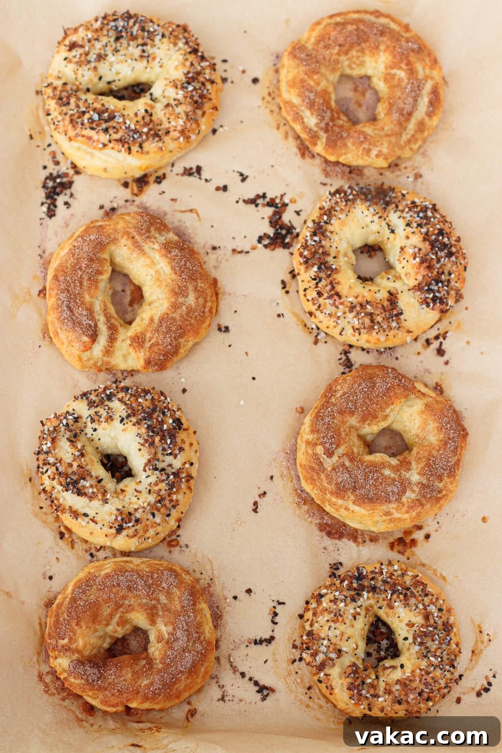 High-Protein Cottage Cheese Bagels Recipe for Homemade Bagels 9 Eight homemade bagels, some topped with everything seasoning and others with cinnamon sugar, are arranged in two rows on a parchment-lined baking sheet. The bagels are golden brown and freshly baked.