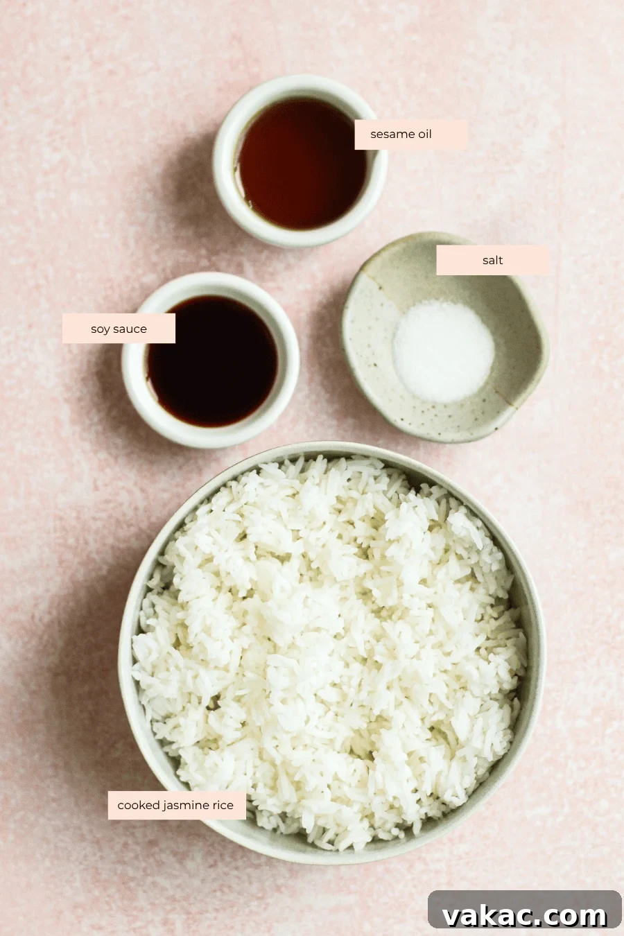 Crispy Sheet Pan Rice for Salads, Bowls and Toppings 3 A bowl of cooked jasmine rice with small bowls containing soy sauce, sesame oil, and salt arranged on a light pink surface. Each ingredient is labeled with text.
