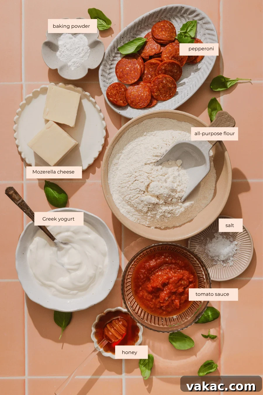 Protein-Packed Greek Yogurt Pizza Dough 4 Bowls of flour, baking powder, salt, Greek yogurt, tomato sauce, honey, mozzarella cheese, and pepperoni slices are arranged neatly on a pink tile surface, garnished with fresh basil leaves.