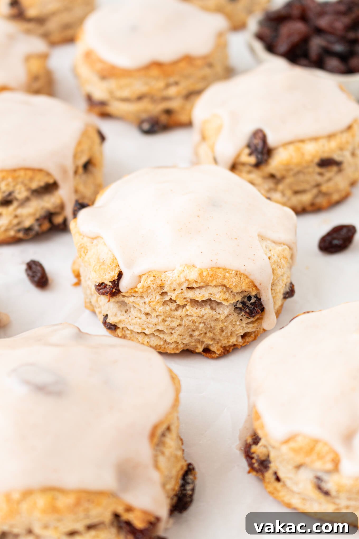 Fluffy Cinnamon Raisin Biscuits with Brown Sugar Glaze 2 Cinnamon raisin biscuits topped with cinnamon icing on a marble countertop.