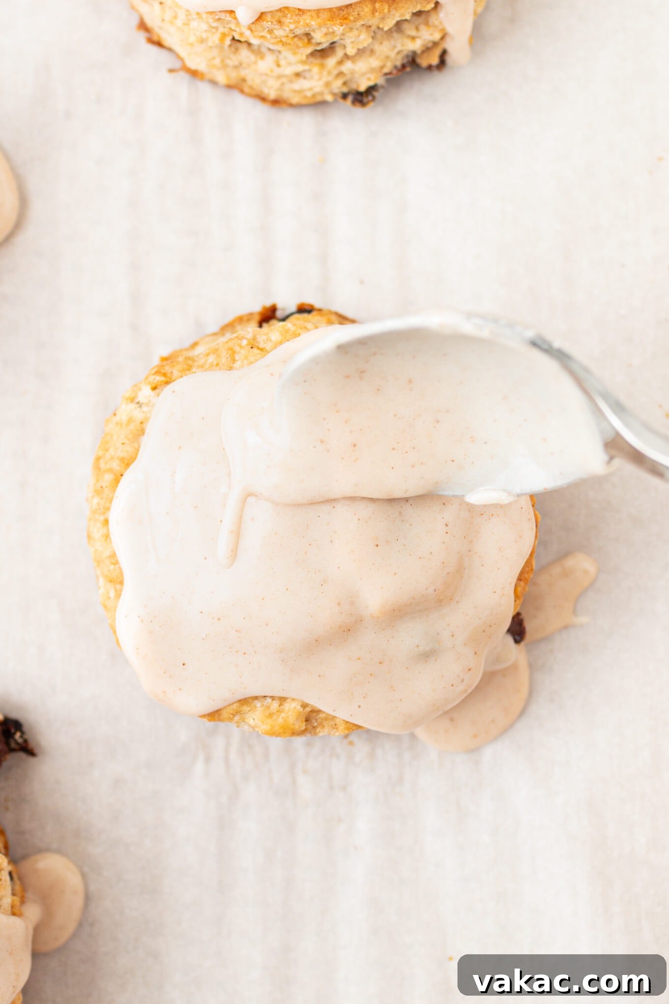 Fluffy Cinnamon Raisin Biscuits with Brown Sugar Glaze 11 A cinnamon and raisin biscuit being drizzled with cinnamon icing.