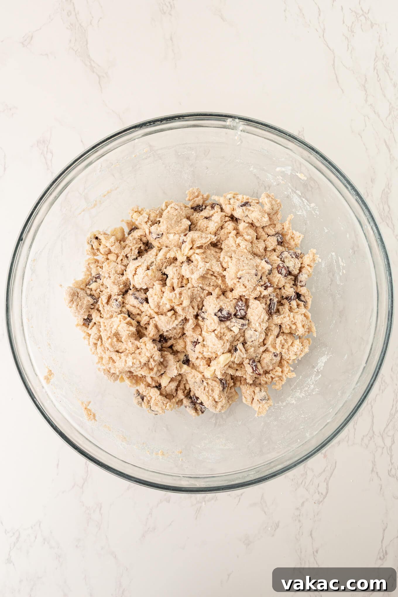 Fluffy Cinnamon Raisin Biscuits with Brown Sugar Glaze 5 An overhead view of cinnamon raisin biscuit dough in a glass mixing bowl.