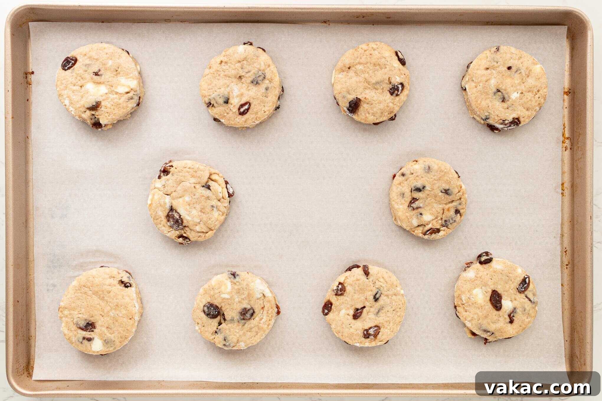 Fluffy Cinnamon Raisin Biscuits with Brown Sugar Glaze 9 An overhead view of unbaked cinnamon raisin biscuits on a parchment lined baking sheet.