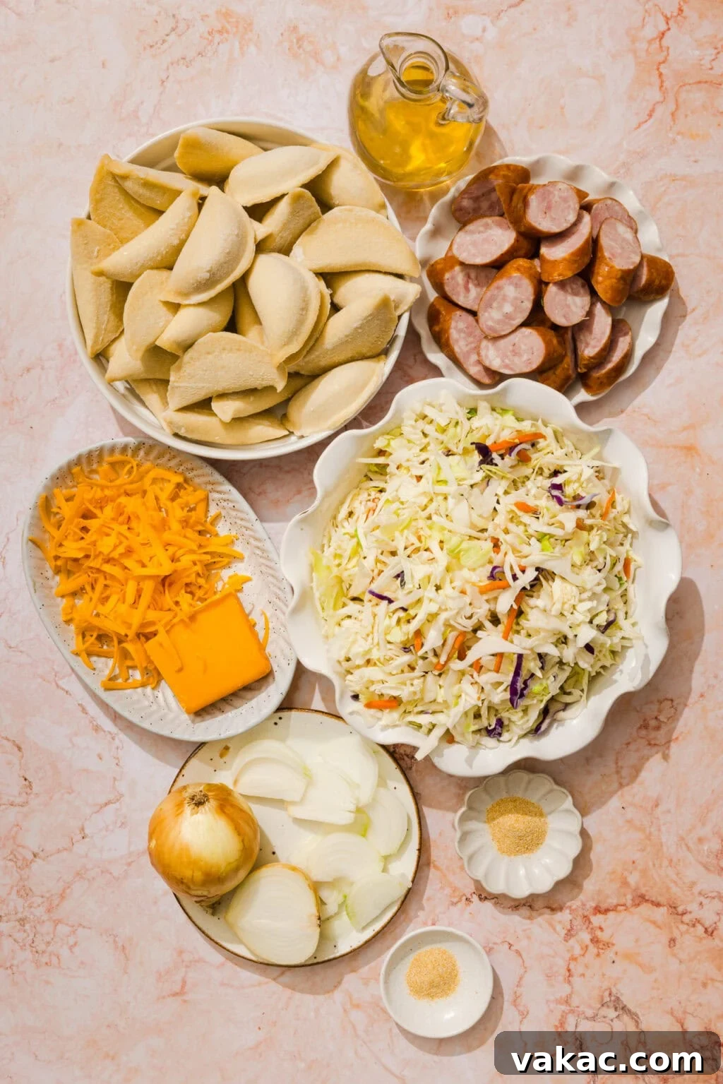 Sheet Pan Kielbasa and Pierogies from Frozen to Crispy 3 A flat lay of ingredients including pierogi, sliced sausage, shredded cheese, coleslaw mix, sliced onion, oil in a jar, and small bowls of seasonings on a light marble surface.