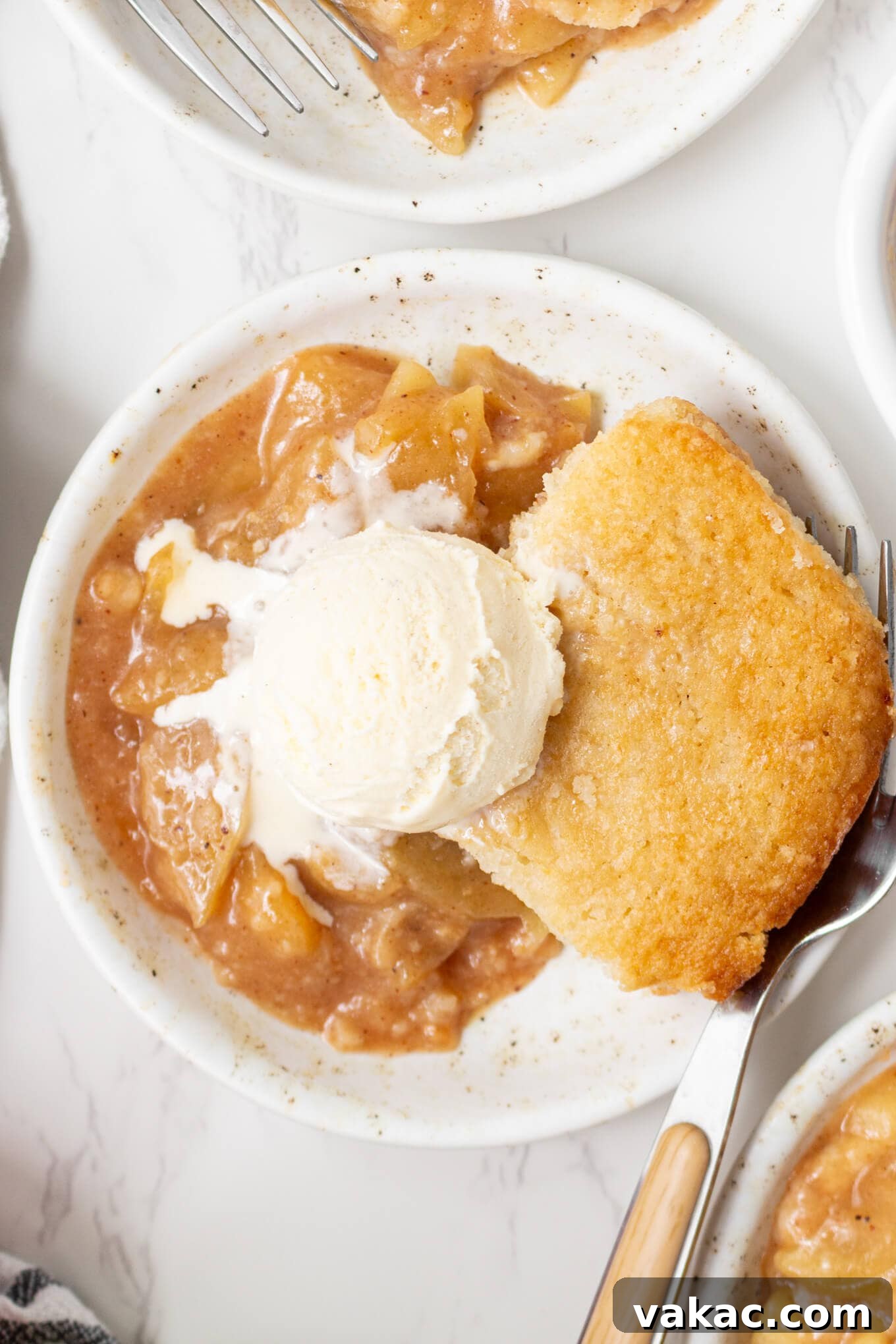 Classic Apple Cobbler with Cinnamon Crumble 2 A serving of apple cobbler topped with ice cream on a dessert plate.