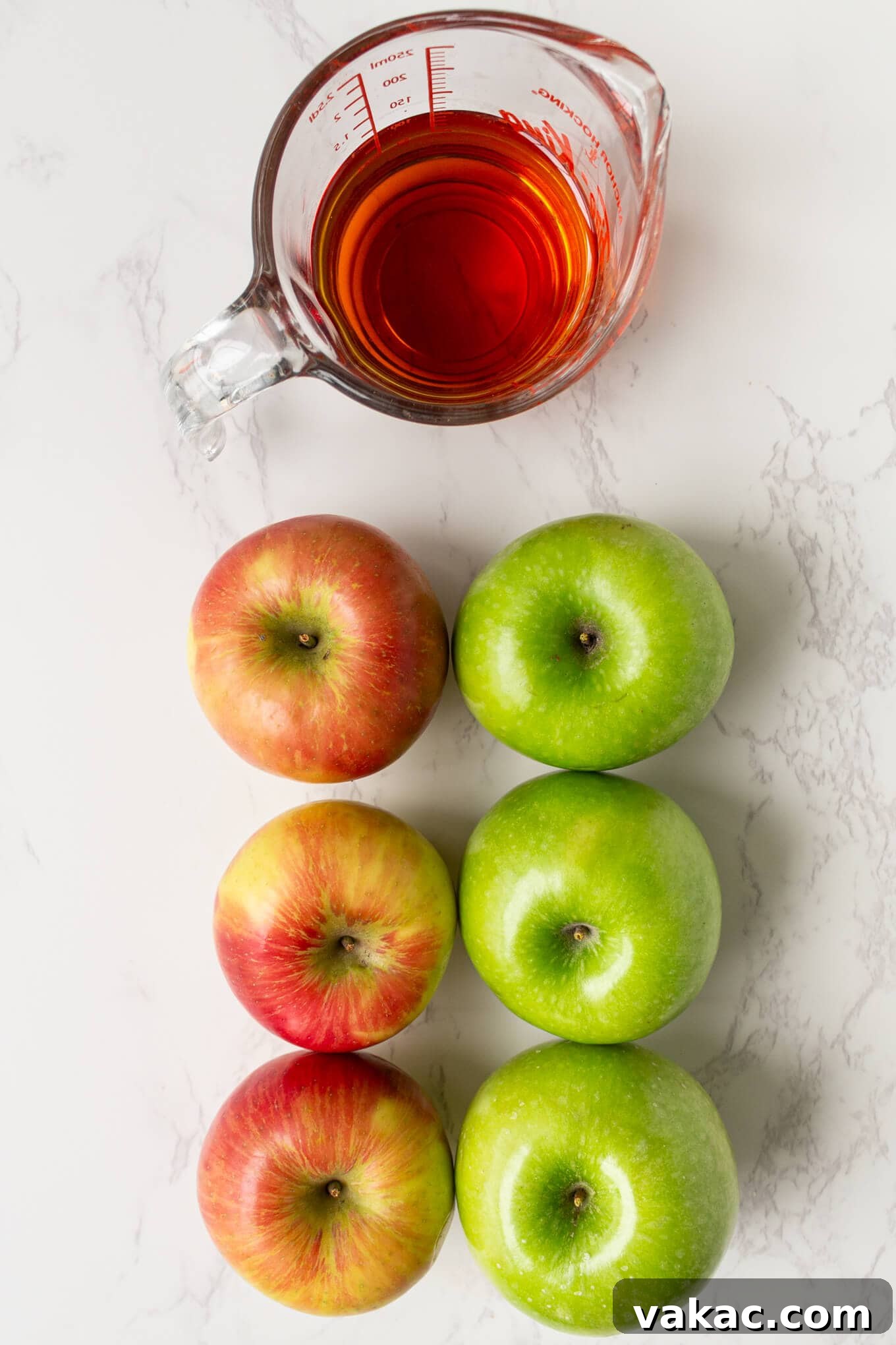 Classic Apple Cobbler with Cinnamon Crumble 3 Six apples and apple cider on a countertop.