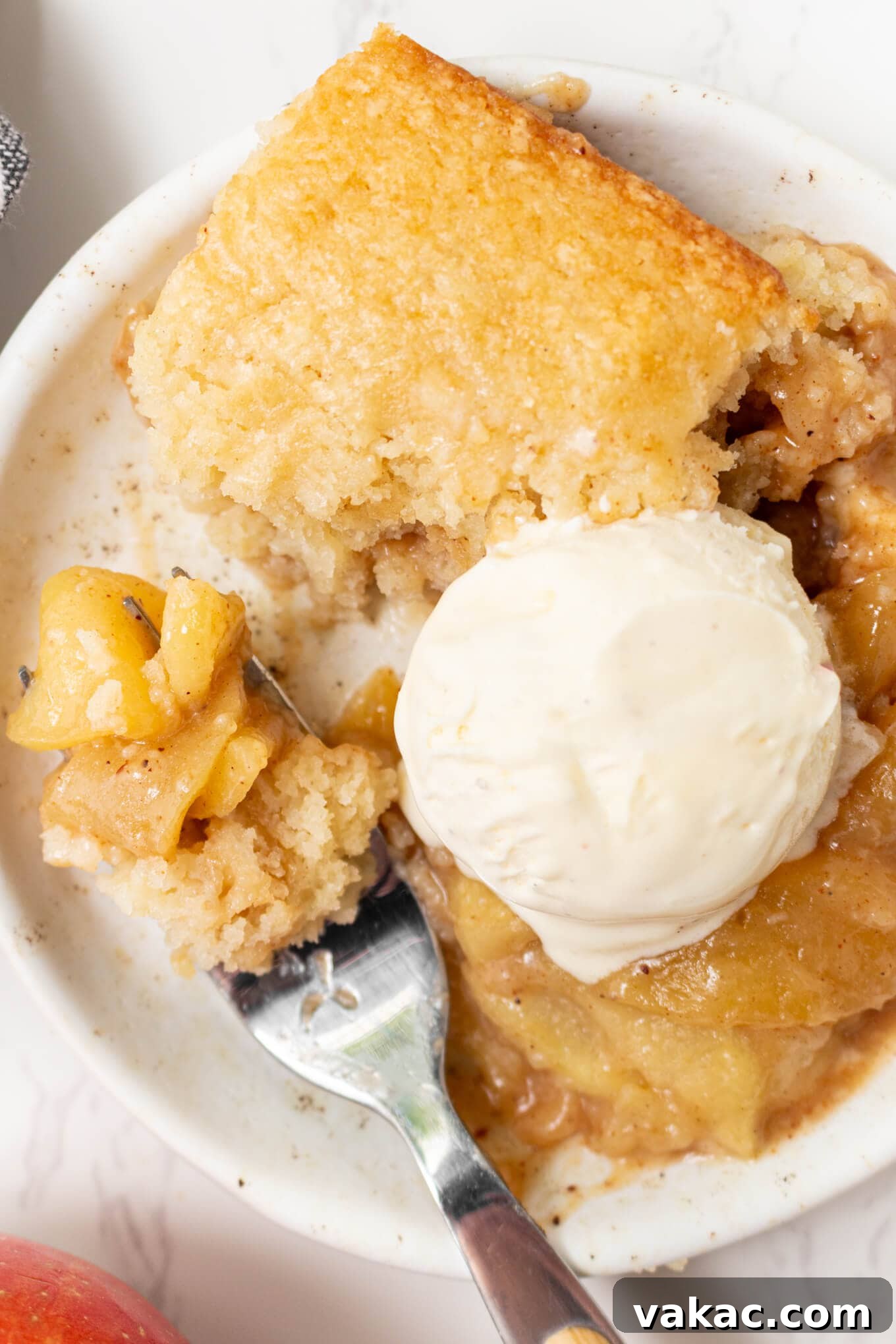 Classic Apple Cobbler with Cinnamon Crumble 9 A serving of apple cobbler topped with ice cream on a dessert plate.