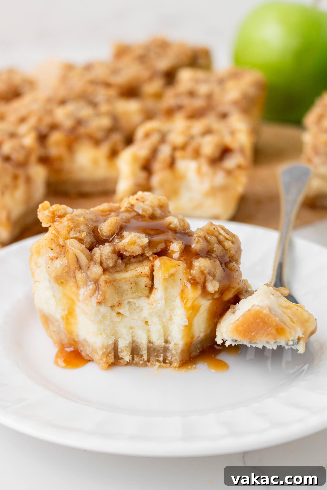 Caramel Apple Cheesecake Bars with Cinnamon Crust 9 A caramel apple cheesecake bar on a plate. A bite is missing.